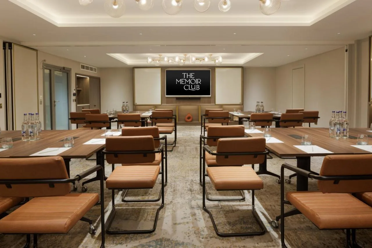 a conference room with tables and chairs and a projection screen at The Memoir Club in London