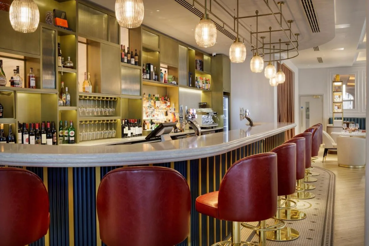 a bar with red chairs in a restaurant at The Memoir Club in London